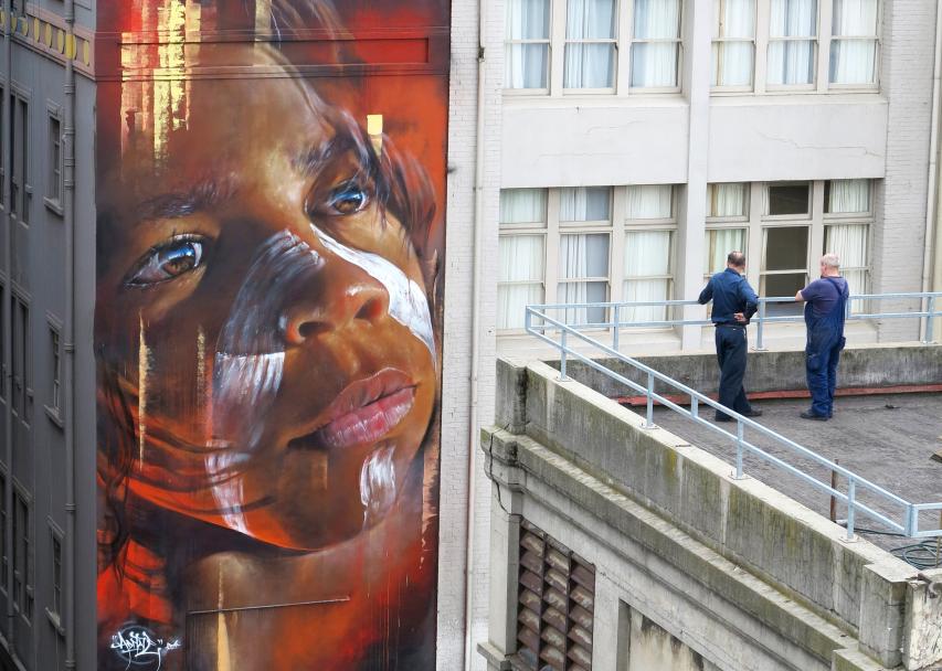 A photo of two workmen admiring a mural by artist, Adnate